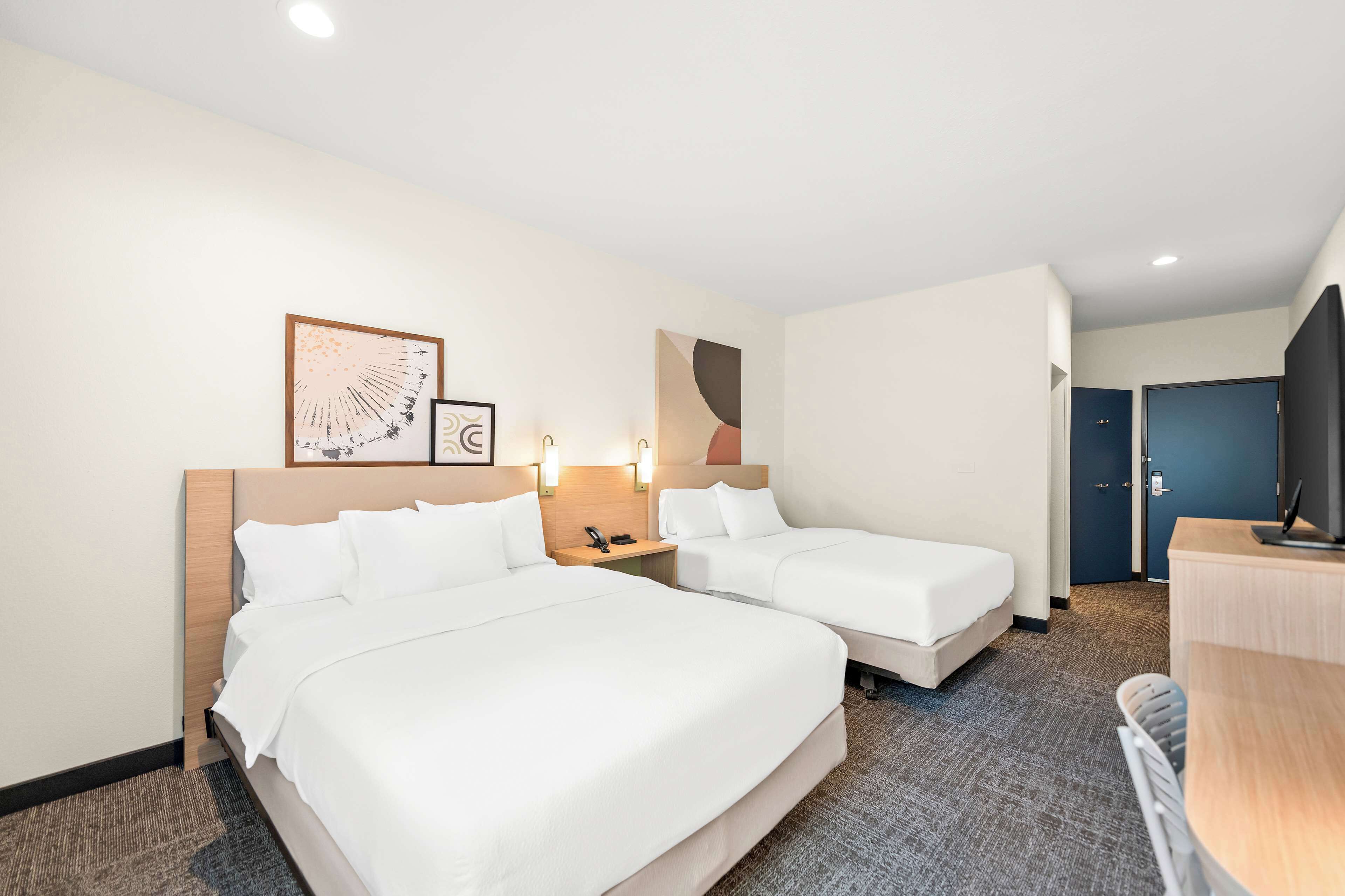 A hotel room with two beds, a desk, and a TV.