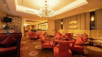 A lobby with red seating, a chandelier, and a bar area.