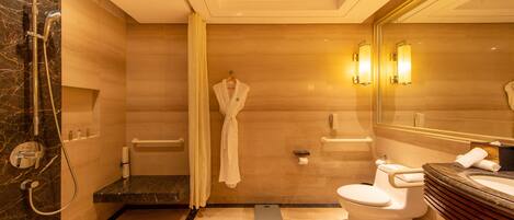A modern bathroom with a marble shower, a toilet, and a vanity with a mirror.