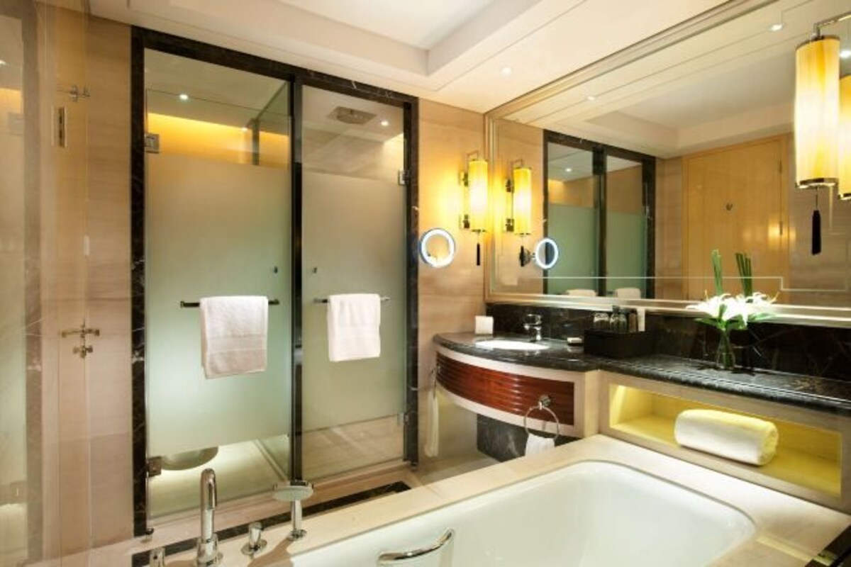 Ein modernes Badezimmer mit Glasdusche, einem großen Spiegel und einer Badewanne.