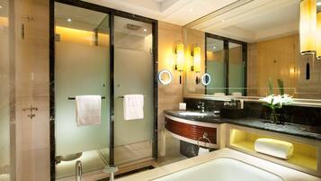 Une salle de bain moderne dotée d’une grande baignoire, d’une douche à parois de verre et d’un meuble-lavabo avec un plan de travail en marbre.