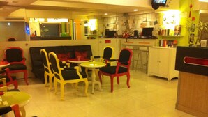 A restaurant with a booth seating area, a bar, and a counter with a TV. - The Inn Saladaeng (Bangkok)