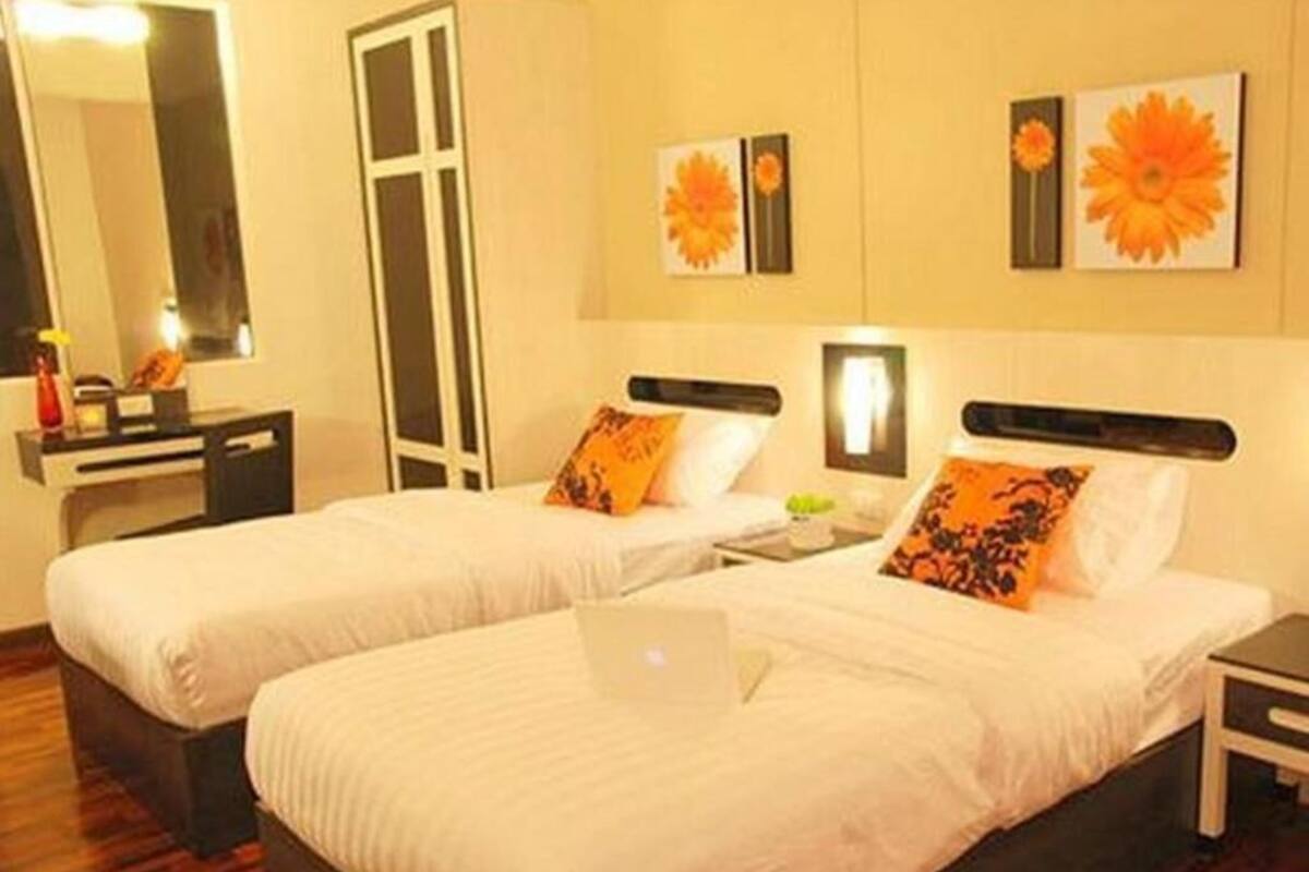 Een hotelkamer met twee bedden, een bureau, een spiegel en kunst aan de muren.