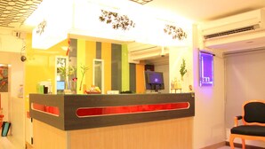 A reception desk with a modern design, a flat-screen TV, and a seating area with a chair. - The Inn Saladaeng (Bangkok)