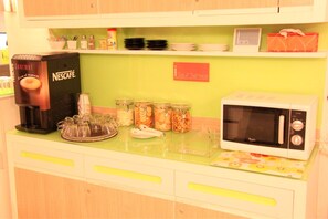 A kitchenette with a Nescafé coffee machine, a microwave, and various food containers.
