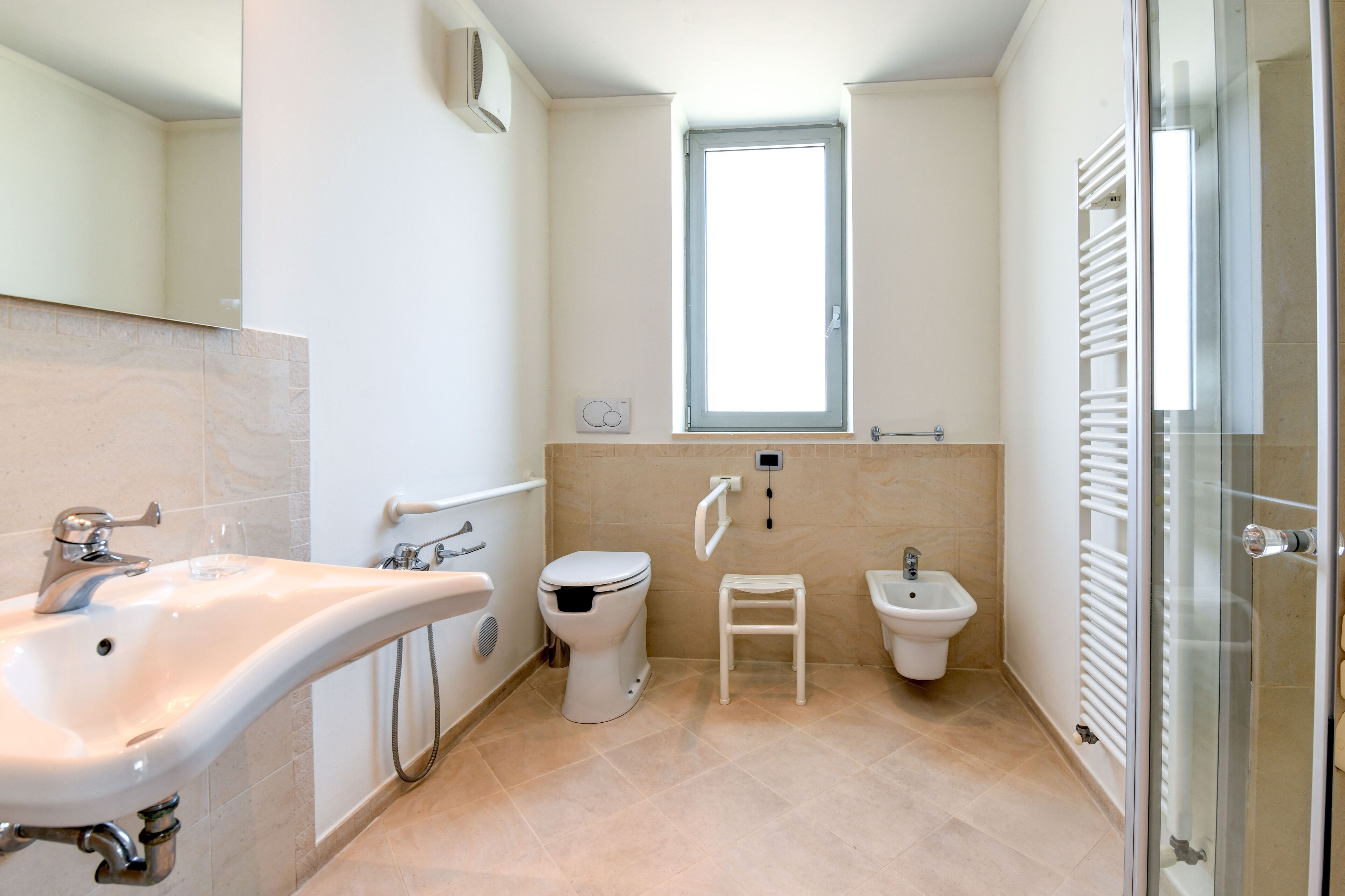 Un bagno moderno con lavandino, WC, bidet e cabina doccia in vetro.