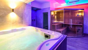 A modern spa room with a hot tub, wooden sauna, and a glass-enclosed shower area. - Hotel Rivus (Peschiera del Garda)