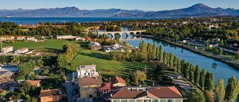 Un grand bâtiment à étages, doté d’un parking et offrant une vue sur une rivière et des montagnes en arrière-plan.
