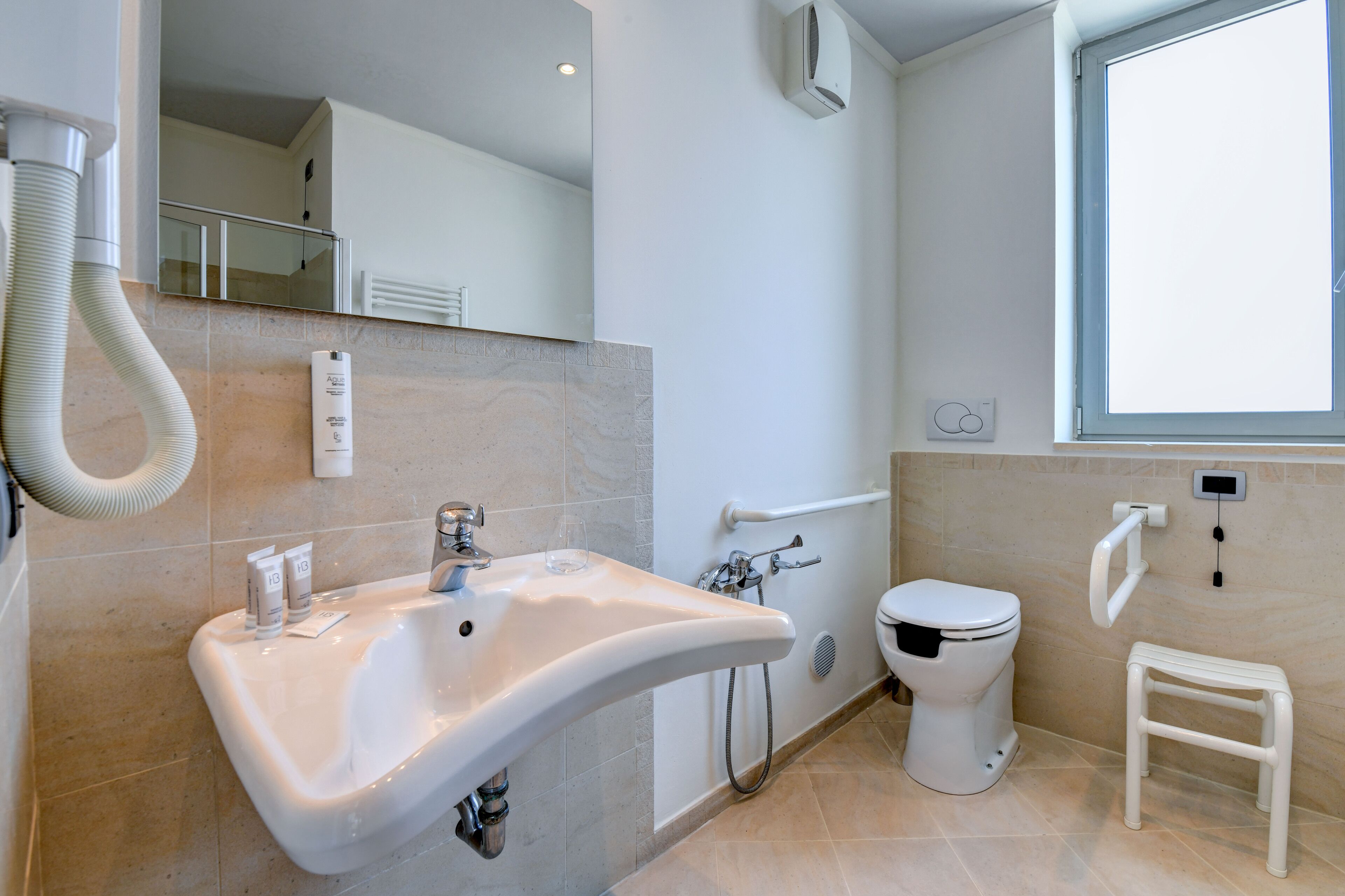 Une salle de bain moderne avec un lavabo incurvé, des toilettes et un petit marchepied.