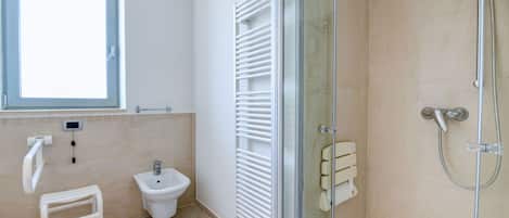 A modern bathroom with a bidet, a glass shower enclosure, and a small stool.