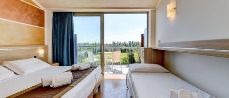 A hotel room with two beds, a large sliding glass door to an outdoor area, and a view of the outdoors.