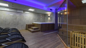 A modern spa room with a massage chair area, a wooden sauna, and a glass partition. - Hotel Rivus (Peschiera del Garda)
