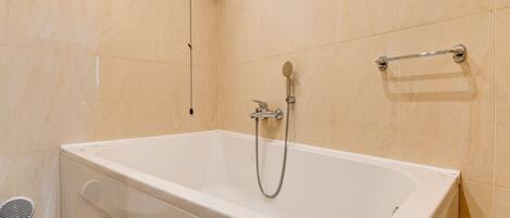 A modern bathroom with a white bathtub, a handheld showerhead, and a grab bar on the wall.