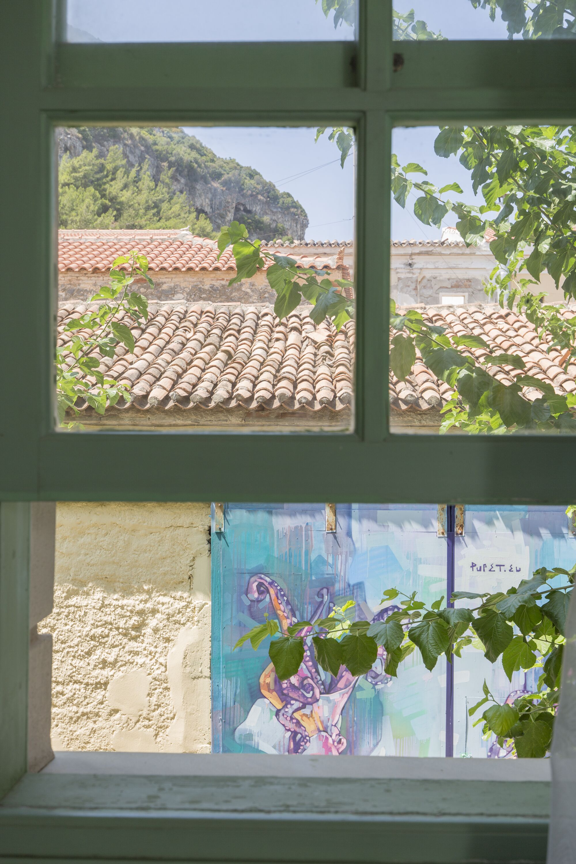 A window view of a building with a tiled roof and a mural on the wall.