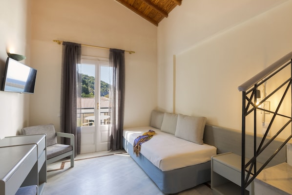 A bedroom with a bed, a chair, a desk, and a TV.