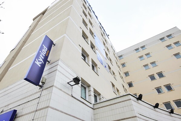 Un edificio de hotel con un llamativo letrero de 'Kyriad Hotel'.