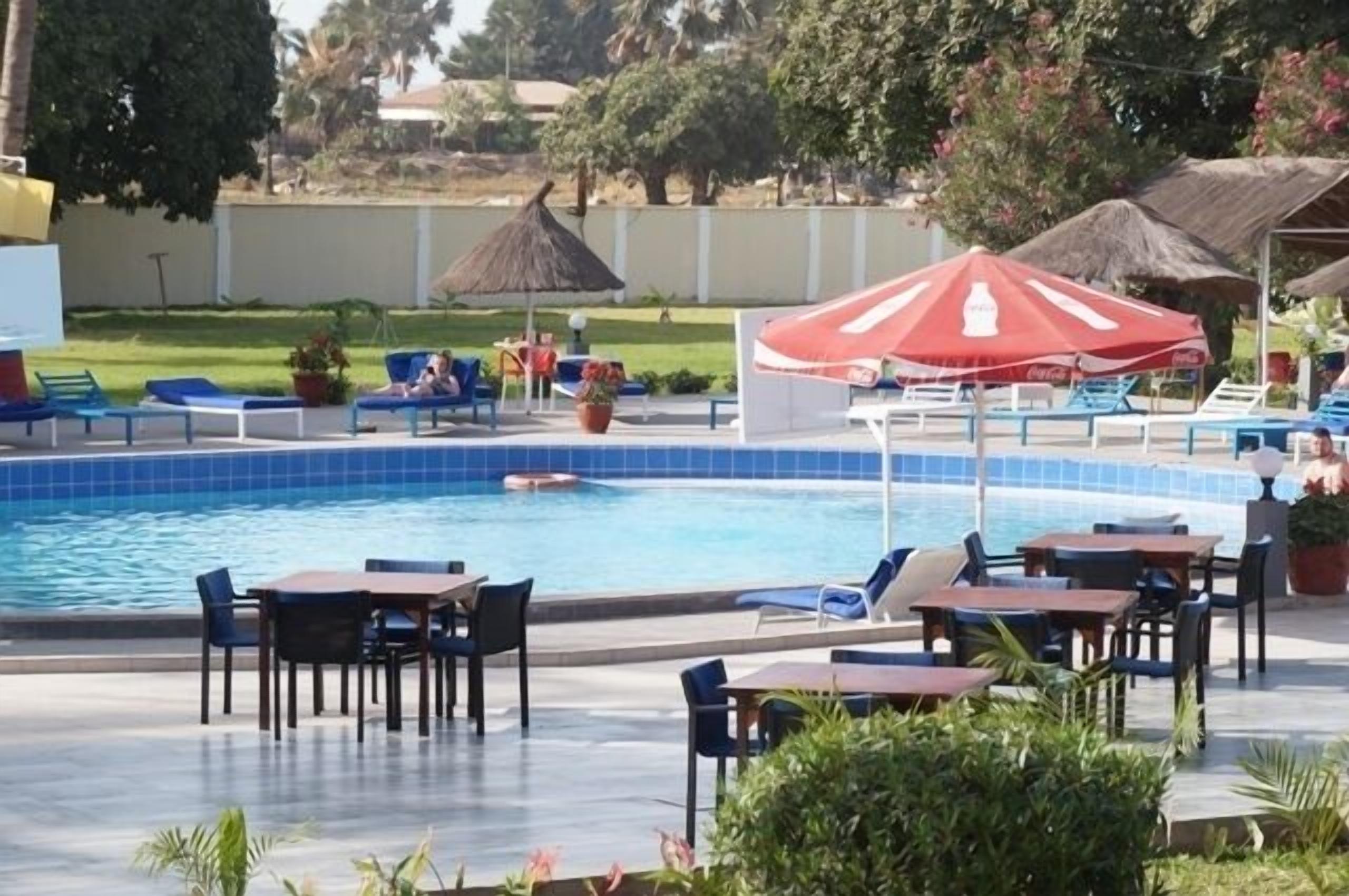 A poolside area with lounge chairs, tables, and umbrellas.
