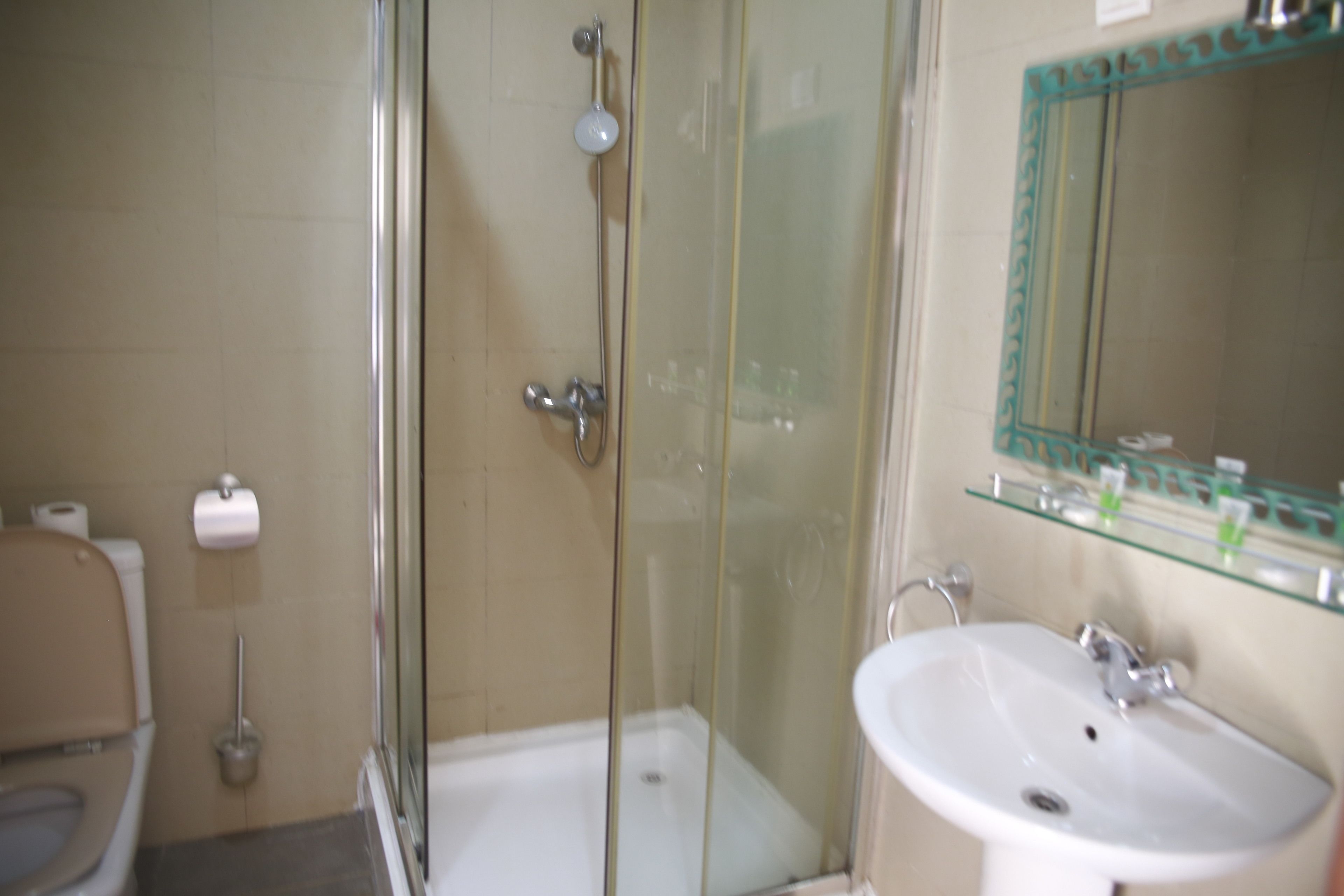 Ein Badezimmer mit einer Duschkabine, Toilette und Waschbecken mit Spiegel.