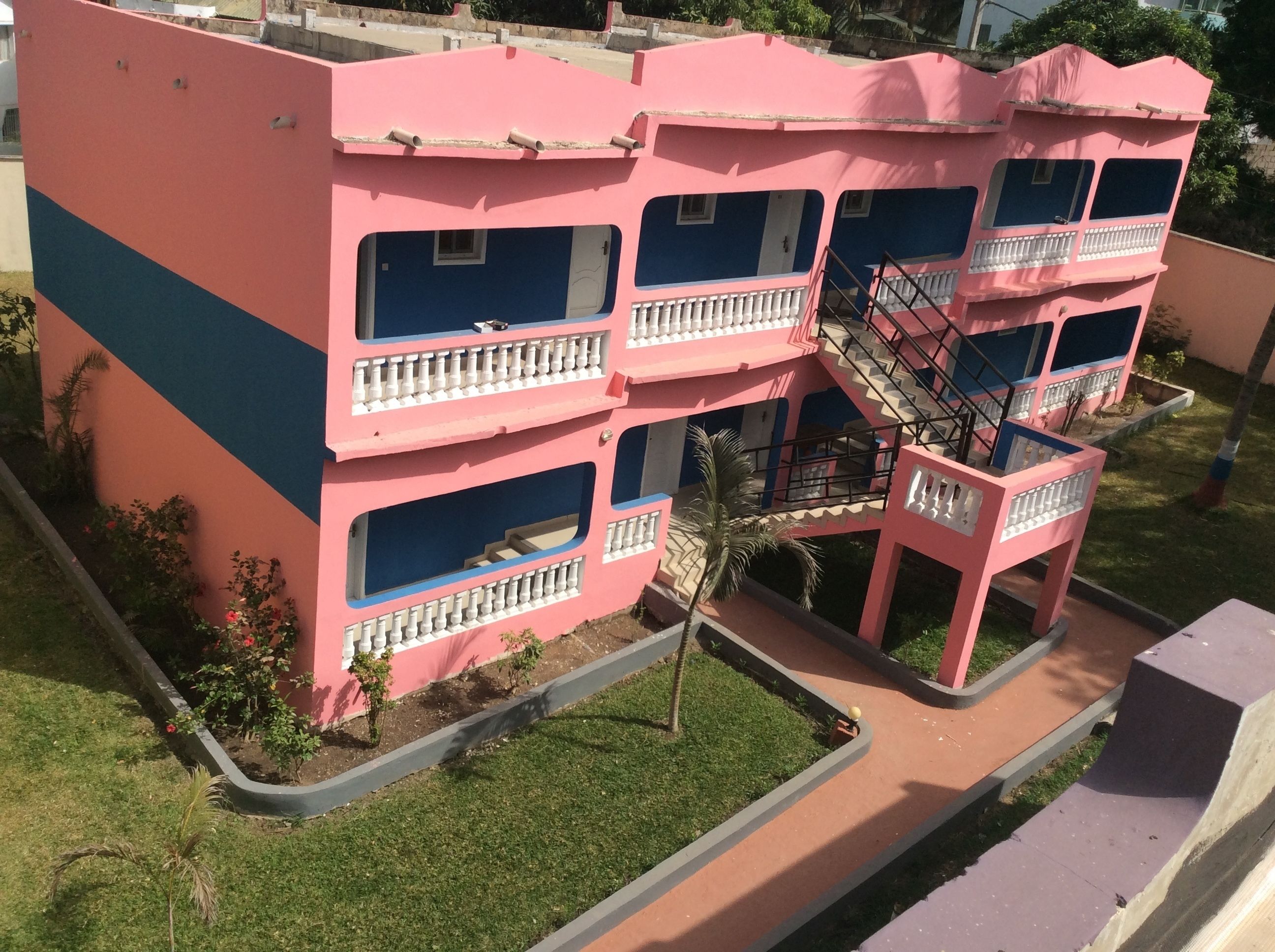 Un edificio de varios pisos de color rosa y azul, con balcones y una escalera.