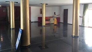 A spacious lobby with high golden columns, a red sofa, and a signboard.