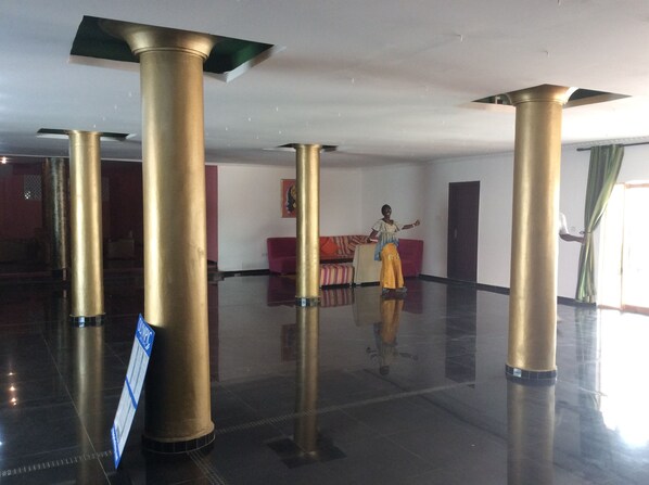 A spacious lobby with high golden columns, a red sofa, and a signboard.