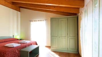 Una camera da letto con un letto, un armadio verde, una panca e una finestra con tende.