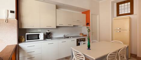 Una cocina compacta con gabinetes blancos, un microondas, un lavamanos y una mesa de comedor con sillas.
