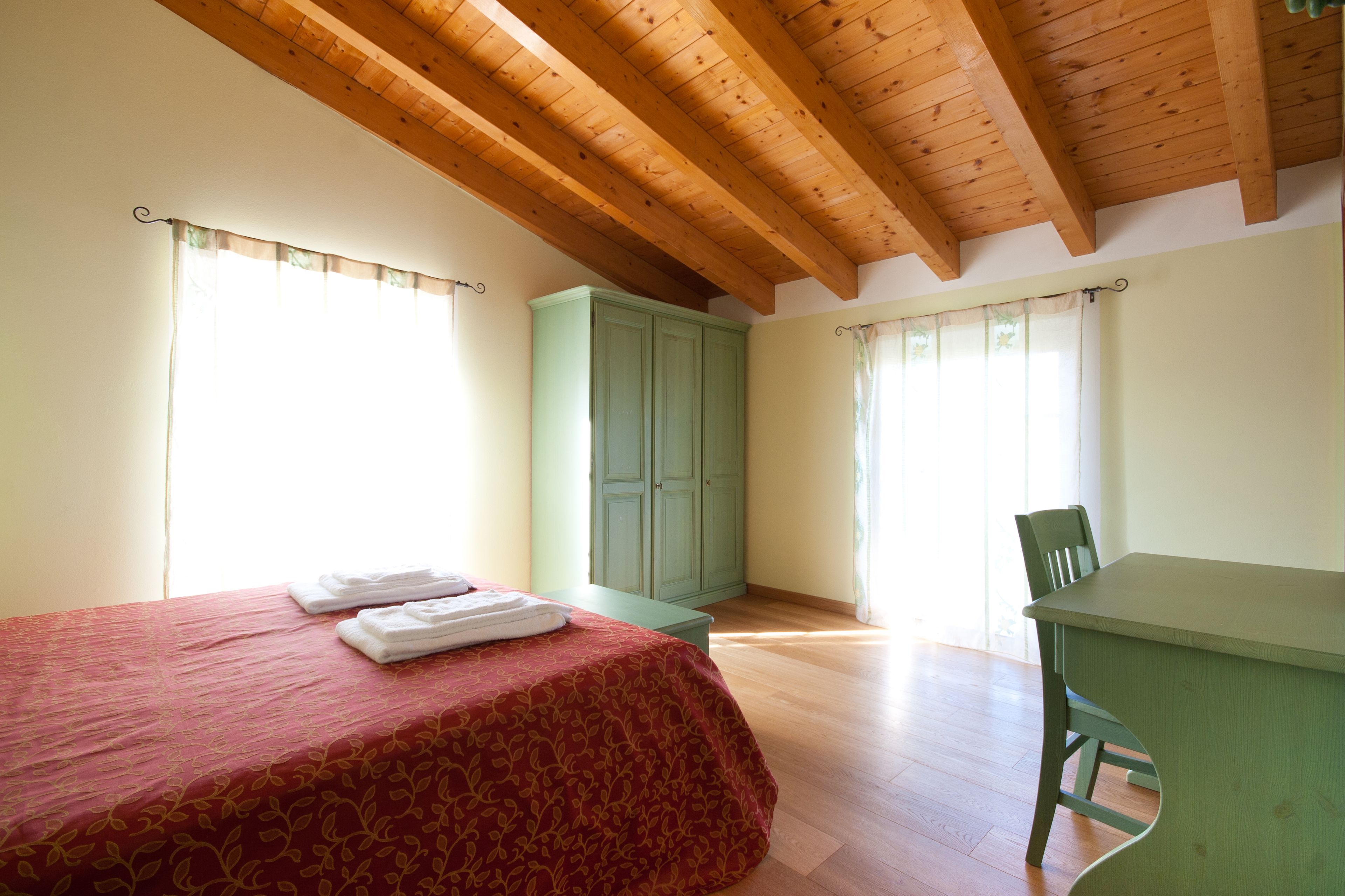 A bedroom with a bed, a desk, and a wardrobe.