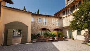 A courtyard with a stone building, a wooden door, and potted plants. - Barchi Resort - Apartments & Suites (San Felice del Benaco)
