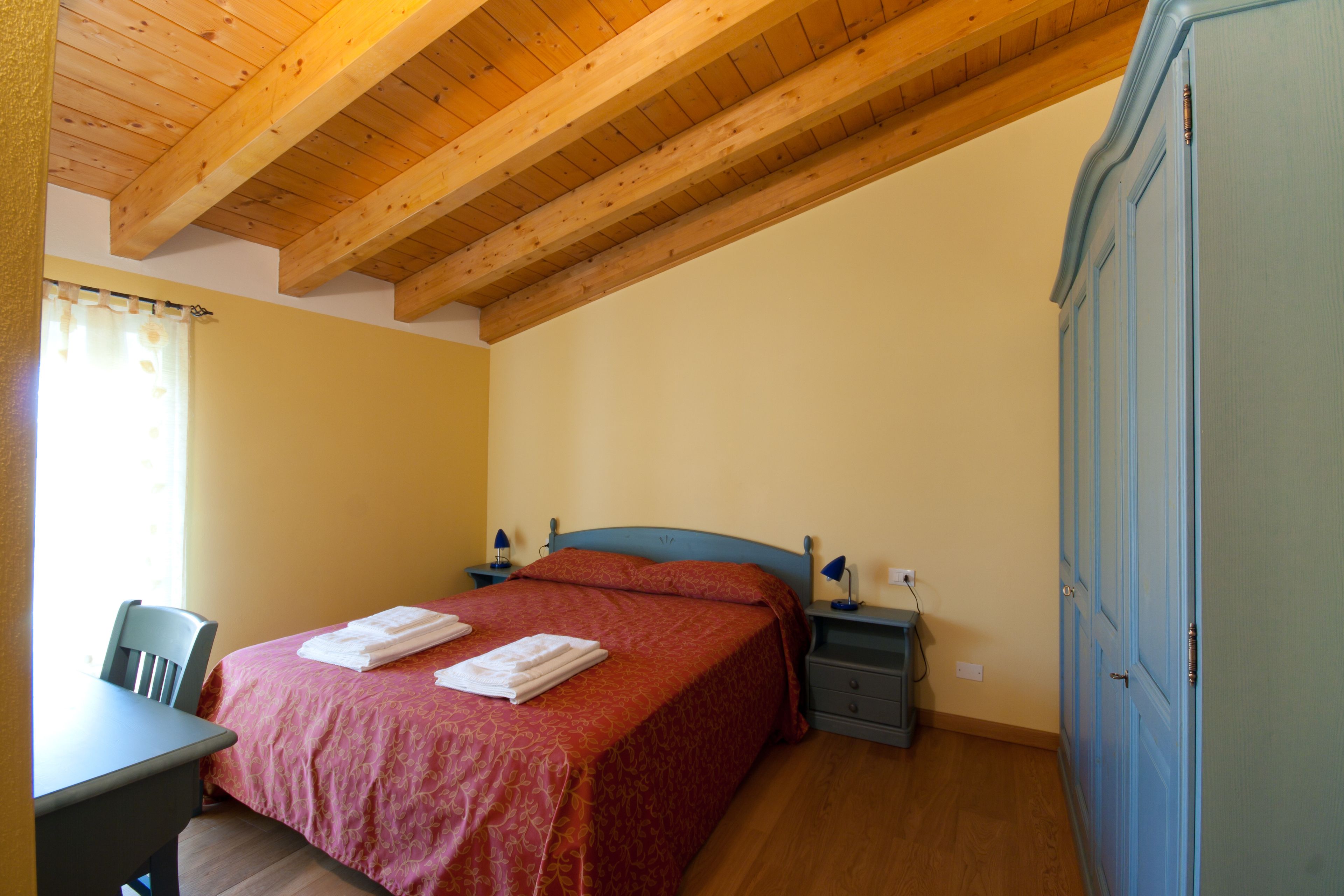 Ein Schlafzimmer mit Bett, Nachttischen, Schreibtisch und Kleiderschrank.