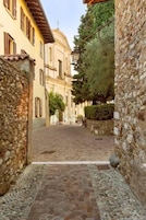 Una estrecha calle adoquinada bordeada por muros de piedra y edificios con ventanas de arco.
