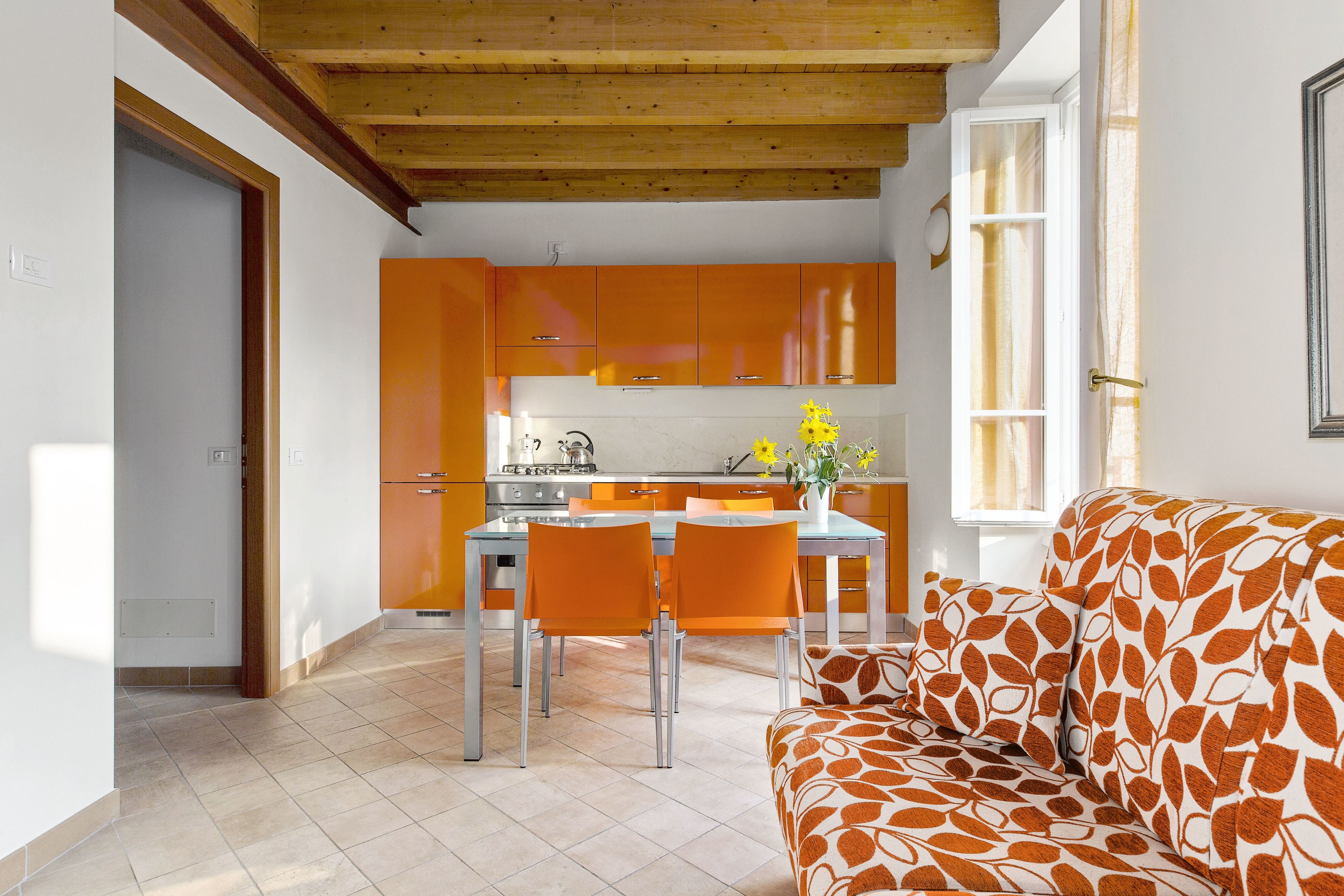 Eine moderne Küche mit orangenen Schränken und einem Essbereich mit einer Couch.