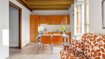Eine moderne Küche mit orangenen Schränken und einem Essbereich mit einer Couch.