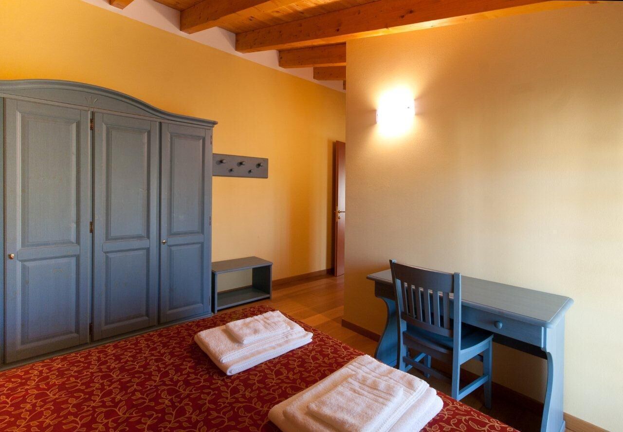 A bedroom with a bed, a desk, a chair, and a wardrobe.