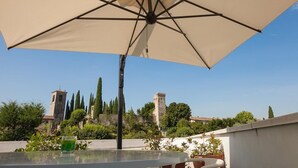 An outdoor patio with a large umbrella, a table, and a glass of drink. - Barchi Resort - Apartments & Suites (San Felice del Benaco)