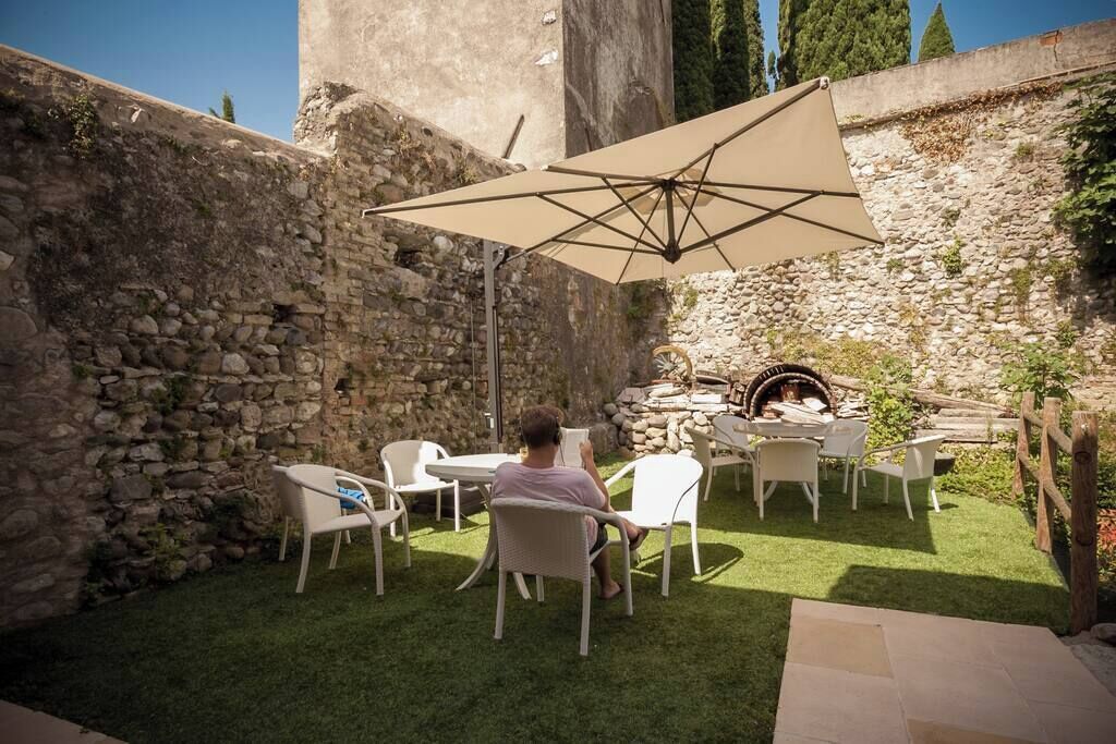 Un'area salotto all'aperto con muri in pietra, un barbecue e un ombrellone grande.