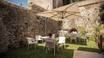 An outdoor seating area with stone walls, a grill, and a large umbrella.