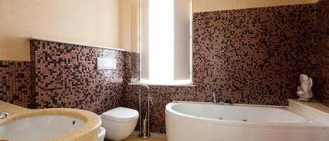 Et badeværelse med et fristående badekar, toilet og vask.
