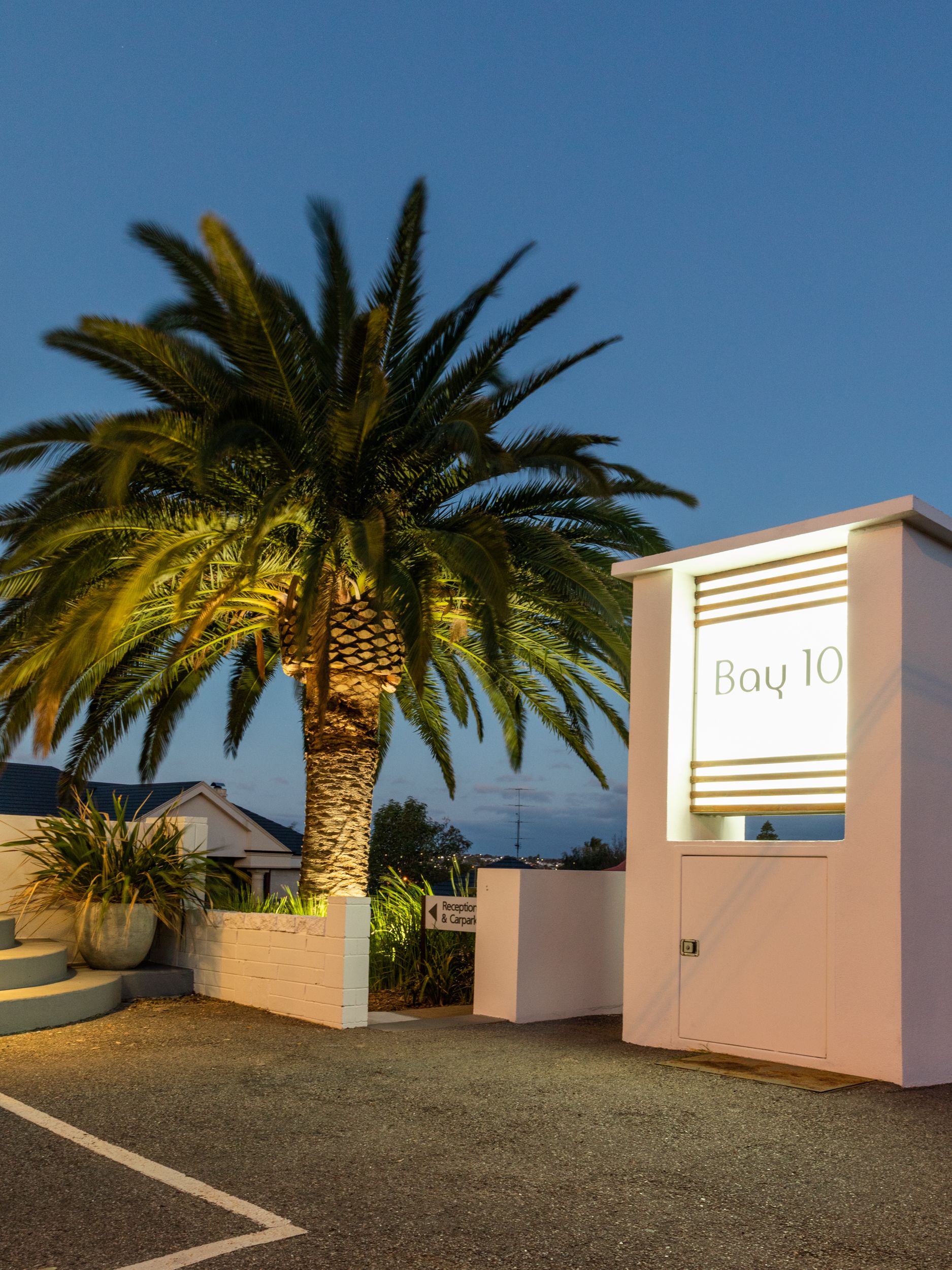 A building with a sign reading "Bay 10" and a palm tree in front.