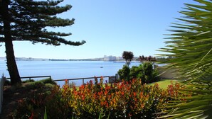 A coastal view with a clear sky, a body of water, and a distant cityscape. - Bay 10 Accommodation (Port Lincoln)