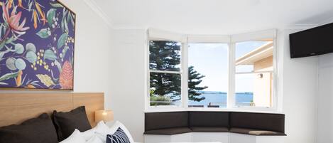 Une chambre dotée d’un grand lit, d’une baie vitrée offrant une vue dégagée, d’un ventilateur de plafond et d’un téléviseur fixé au mur.