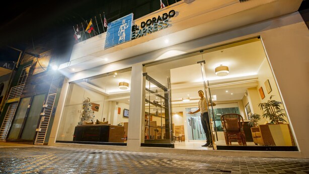 A hotel entrance with a glass door, a reception desk, and a sign reading "El Dorado Express".
