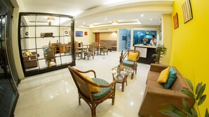 A hotel lobby with a seating area, a reception desk, and a glass partition wall.