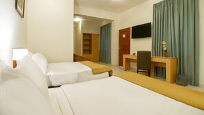 A hotel room with two beds, a desk, a chair, a TV, and a bathroom visible through an open door.