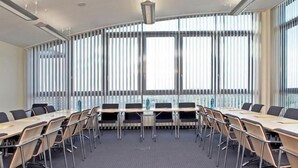 A conference room with a long table, chairs, and large windows with blinds.