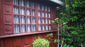 A red wooden wall with a grid of windows, potted plants, and a bench. - Zuetana 106 (Bogotá)