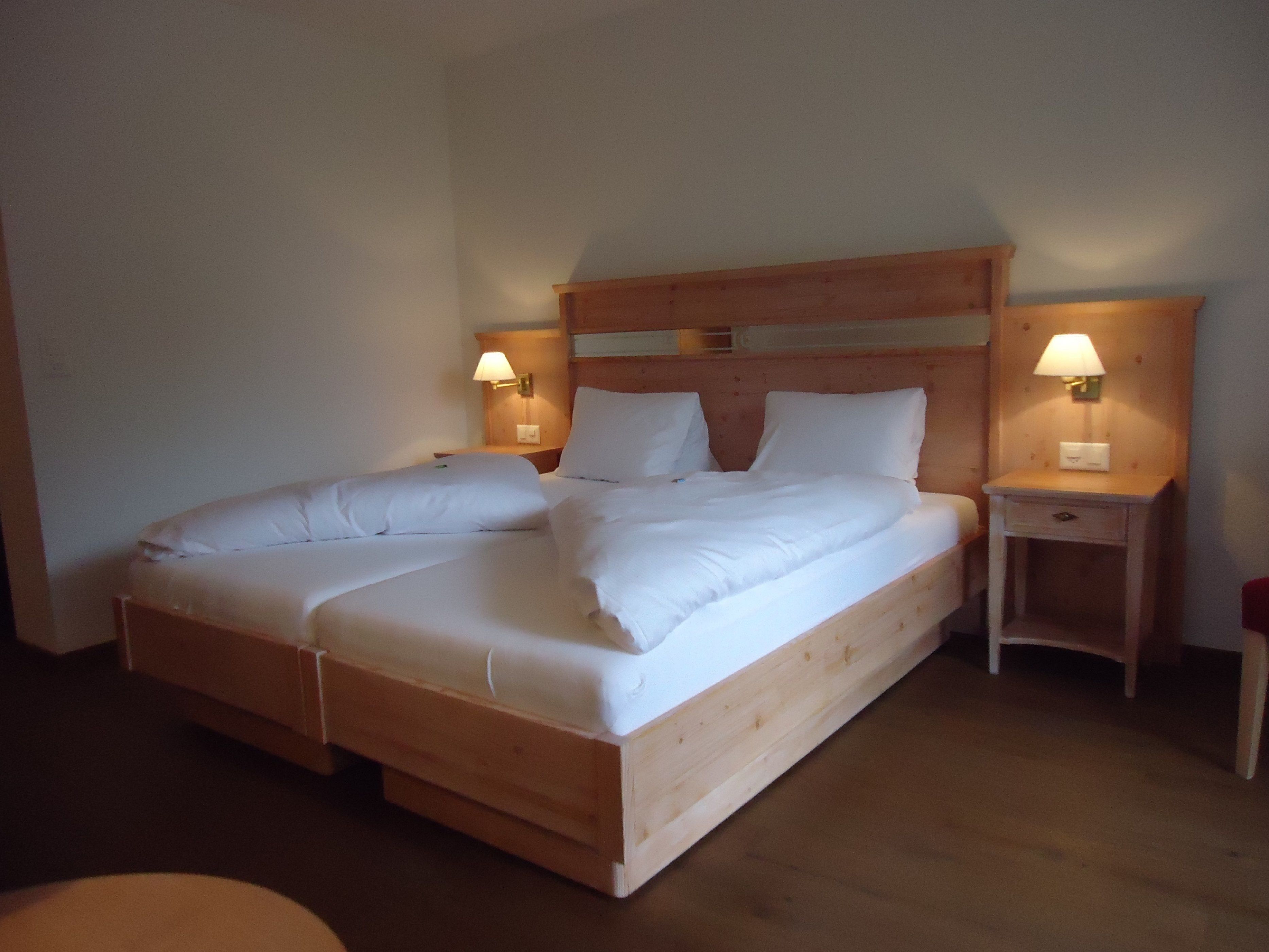 Una cama doble con cabecera de madera y dos mesitas de noche con lámparas.