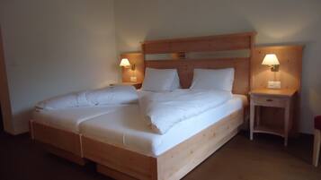Una cama doble con cabecera de madera y dos mesitas de noche con lámparas.