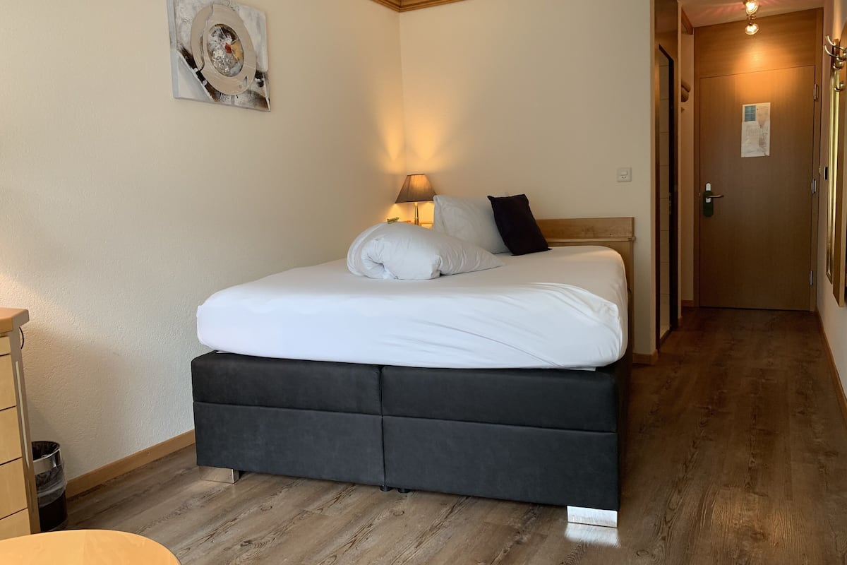 A neatly made bed with white linens and a black headboard in a hotel room.