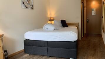 A neatly made bed with white linens and a black headboard in a hotel room.